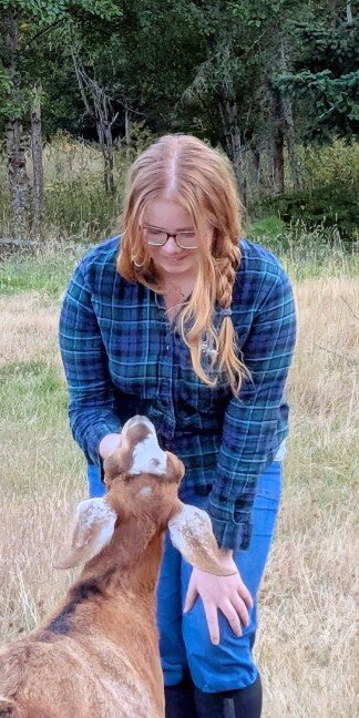 Isabella petting a brown goat